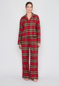 Rood geruite pyjama-set gemaakt van zachte stof, met een knoopsluiting shirt en losse broek, met zwarte en gele lijnen in het patroon.