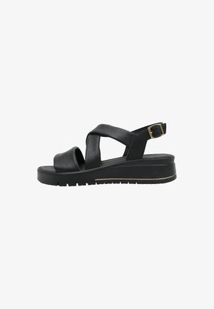 Sandale plateforme noire avec brides croisées, bout ouvert et boucle réglable à la cheville sur semelle épaisse à crampons.