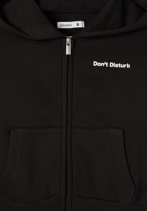 Felpa nera con zip e tasche a marsupio, con la scritta bianca "Non Disturbare" sul lato sinistro del petto e una finitura in tessuto morbido e texture.