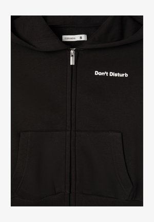 Czarna bluza z kapturem na zamek błyskawiczny z kieszeniami kangurzymi, z białym napisem "Nie przeszkadzać" na lewej piersi oraz miękkim, teksturowanym wykończeniem tkaniny.