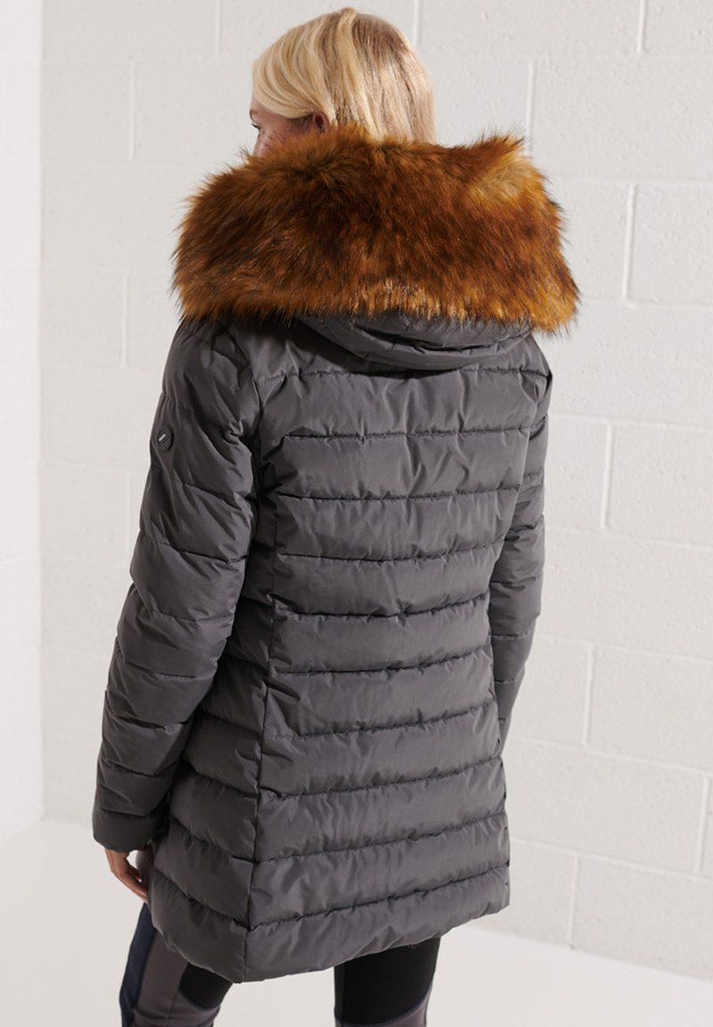 Dikke grijze parka met een afneembare bruine bontkraag, voorzien van horizontale stiksels, zakken en een capuchon. Geweven stof met een gladde afwerking.