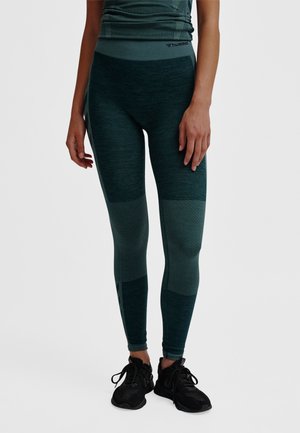 Leggings gjorda av ett texturerat, mörkgrönt material med varierande mönster. Hög midja, figurnära passform och inslag av meshpaneler.