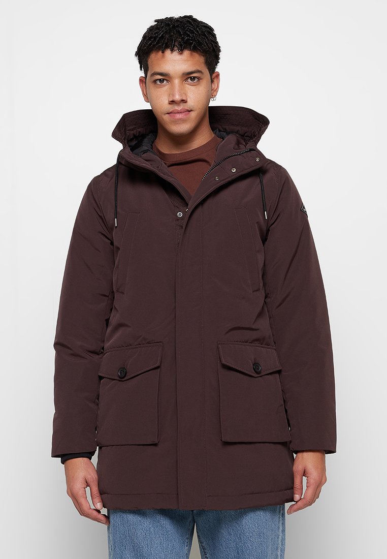 Donkerbruin gewatteerd jack met een capuchon, voorzien van twee voorkruiszakken, een verstelbaar trekkoord en een ritsluiting, gemaakt van een gladde stof.