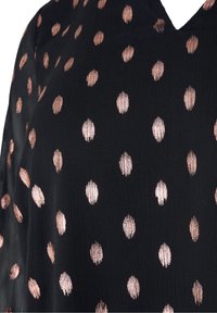 Blusa nera con pois color oro rosa lucido. Il tessuto è leggero con una texture a coste, caratterizzata da un design a scollatura a V.