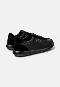 Scarpe sportive nere con tomaia in pelle testurizzata, dettagli lisci, punta tonda e suola in gomma imbottita con piccoli tacchetti antiscivolo.