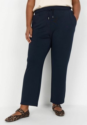 Mörkblå sweatpants med avslappnad passform och elastiskt midjeband; har sidofickor och matchande dragsnöre. Bärs med leopardmönstrade ballerinas.