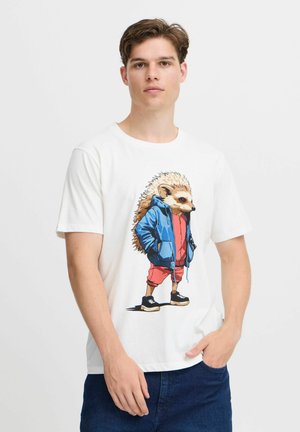 Hvid t-shirt med et tegneserieillustration af et pindsvin iført en blå hættetrøje og røde shorts. Designet inkluderer detaljeret pels og sorte sneakers.