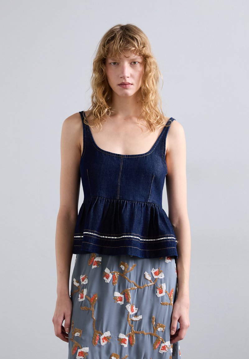 Dunkelblaue Denim-Peplum-Oberteil mit einem runden Ausschnitt und dünnen Trägern, das eine geraffte Taille und kontrastierende Nähte am Saum aufweist.