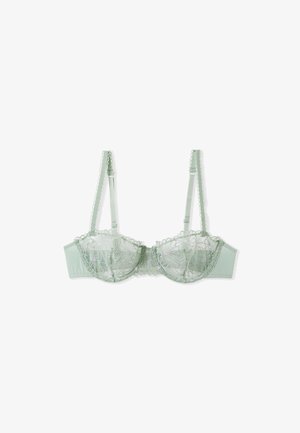 Soutien-gorge en dentelle verte avec un design floral brodé, présentant une structure à armatures, des bretelles réglables et une bande texturée à pois.