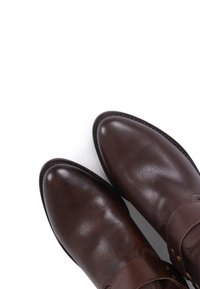 Pair of polished dark brown leather boots with rounded toes and decorative stitching on a white background.