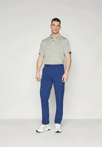 Grårandig polo skjorta med kort ärm, matchad med blåbyxor. Outfiten avslutas med vita sneakers. Minimalistisk och modern design.