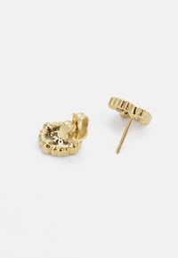 Boucles d'oreilles en or en forme de hoop avec un design texturé et ondulé, et un petit fermoir à clou. Présentent une forme circulaire et des accents alternés en forme de vagues.