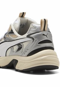 Sneakers Puma w kolorystyce srebrno-biało-czarnej; teksturowane materiały; gruba podeszwa; wyraźne logo marki z boku oraz pętelka do zakładania.