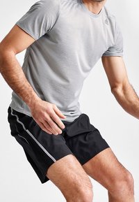 Camiseta atlética gris de manga corta con cuello redondo y pantalones cortos atléticos negros con rayas laterales, ambos hechos de material ligero.