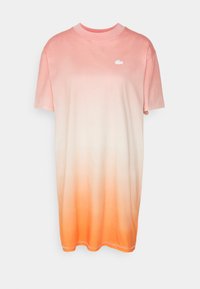 T-shirt à manches courtes avec un effet ombré, passant du rose clair à l'orange. Présente un petit logo blanc en haut à gauche.