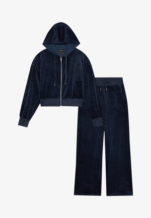Navy blå velour loungewear-sett med en kort zip-up hettejakke med hette og vide bukser, begge med ribbestrikkede mansjetter og snor i livet.