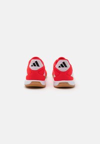 Czerwone buty sportowe z siateczki i materiałów syntetycznych, z amortyzującymi podeszwami oraz czarnymi paskami akcentującymi na pięcie.