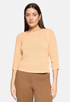 Lyserød ferskenfarvet strikket sweater med trekvartlange ærmer og rund halsudskæring. Har en tekstureret overflade og en kortet kant.