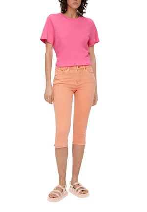T-shirt rose vif à manches courtes associé à un jean court orange clair. La tenue comprend des sandales à plateforme beiges avec plusieurs brides.