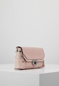 Světle růžová strukturovaná kabelka s texturovanou stranou, kovovými akcenty a trojúhelníkovým zapínáním. Hladký povrch a kompaktní design.