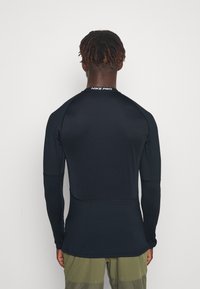 Černé tričko s dlouhým rukávem Nike Pro, přiléhavý střih s texturovanou tkaninou. Obsahuje ploché švy a logo na krku.