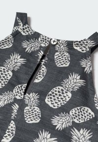 Grauer Stoff mit weißem Ananasmuster; mit einem Knopfverschluss und einem Schlitzdetail am Ausschnitt sowie Schulterakzenten.