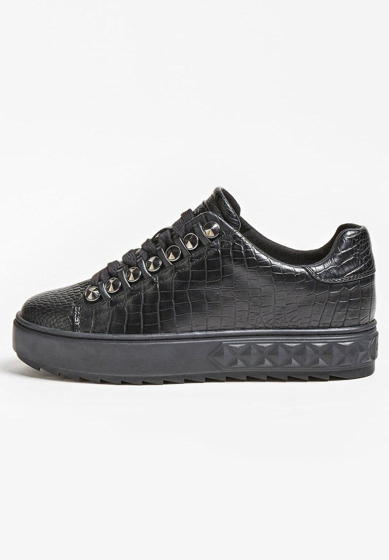 Baskets basses noires avec texture crocodile, œillets métalliques cloutés et semelle épaisse présentant des motifs en pyramide en relief, vues de profil.