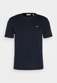 Marineblå bomull T-skjorte med rund hals, korte ermer, og en liten logo brodert på venstre bryst. Myk tekstur, standard passform.
