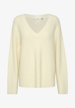 Suéter de punto color crema con cuello en V, mangas largas y corte holgado. Presenta un patrón texturizado y un tejido suave y grueso.