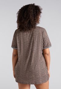 Camisa de noche de estampado de leopardo en tejido suave, con mangas cortas, detalles de ribete negro y un corte relajado. Diseñada para la comodidad y el uso casual.