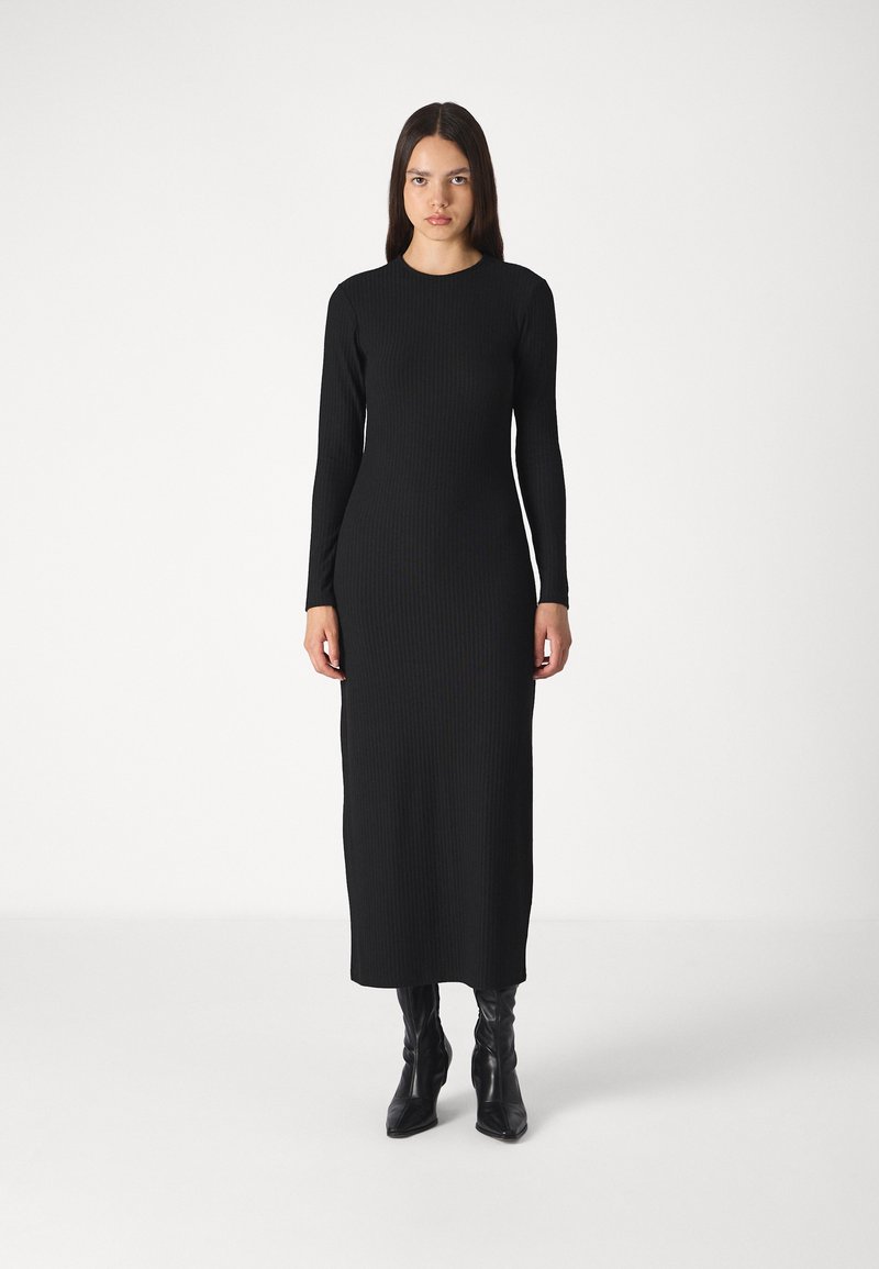 Black ribbed long-sleeve dress with a fitted silhouette, crew neck, and ankle length, paired with black knee-high boots.