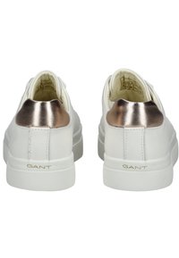 Sneakers bianchi con accenti in oro rosa metallizzato sul tallone, suola in gomma testurizzata e logo dorato impresso sul retro. Parte superiore in pelle liscia.