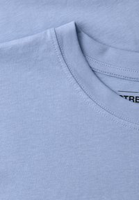 Tissu de T-shirt bleu clair à col rond montrant un gros plan du col et des détails de couture.