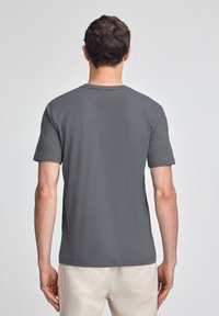 Camiseta gris de manga corta con cuello redondo estándar, hecha de algodón, con una textura lisa y un diseño simple.