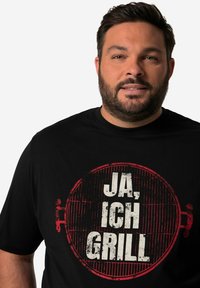 Black t-shirt made of cotton featuring a round grill graphic with red accents and the text "JA, ICH GRILL" in distressed white font.