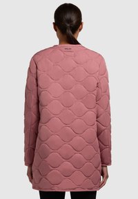 Veste rose matelassée avec un motif en vagues, manches longues et col rond. Le tissu semble lisse avec un léger éclat.