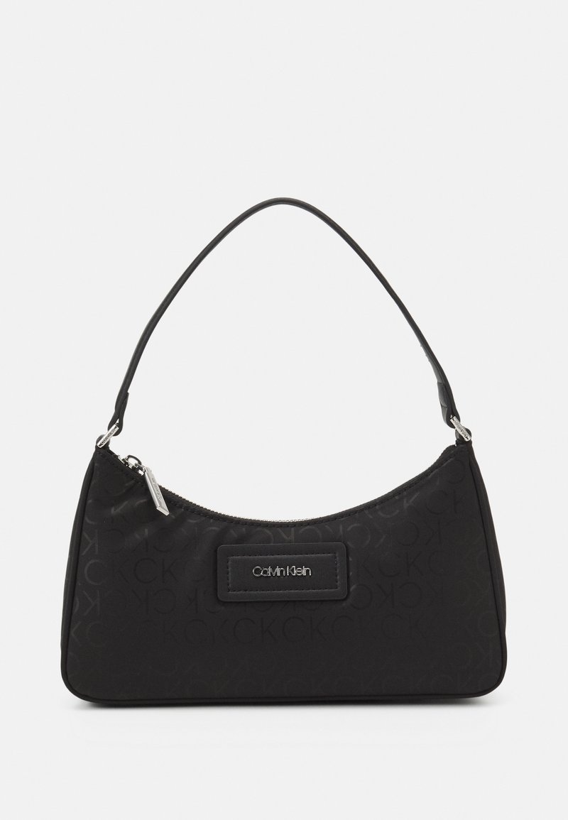 Sac à épaule Calvin Klein noir avec une fermeture éclair incurvée en haut et une plaque logo sur le devant, doté d'une seule bandoulière fine.