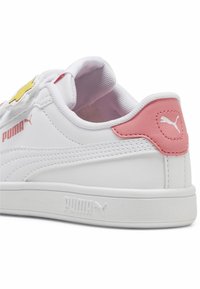 Witte leren sneaker met roze accenten, een gele bloemontwerp op de tong, een textuur stof inlegzool en een witte rubberen zool. Puma-logo aanwezig.