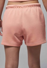Rosa bomullsshorts med en mjuk textur, elastisk midja och uppvikta fållar. Sömmar synliga på baksidan.