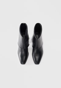 Black leather ankle boots with a pointed toe and a folded cuff design. Smooth texture, minimal hardware, and streamlined silhouette.