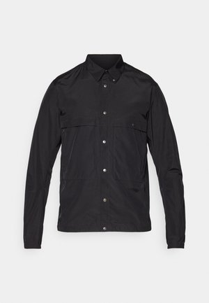 Juodas švarkas, pagamintas iš lengvos medžiagos, su mygtukų užsegimu, smailiu apykakle ir dviem priekinių kišenių. Lygus paviršius, minimalus dizainas.