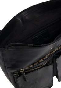 Schwarze Lederhandtasche mit glatter Textur, ausgestattet mit einem Reißverschluss-Hauptfach, mehreren kleineren Reißverschlussfächern und Akzenten aus goldfarbenem Metall.