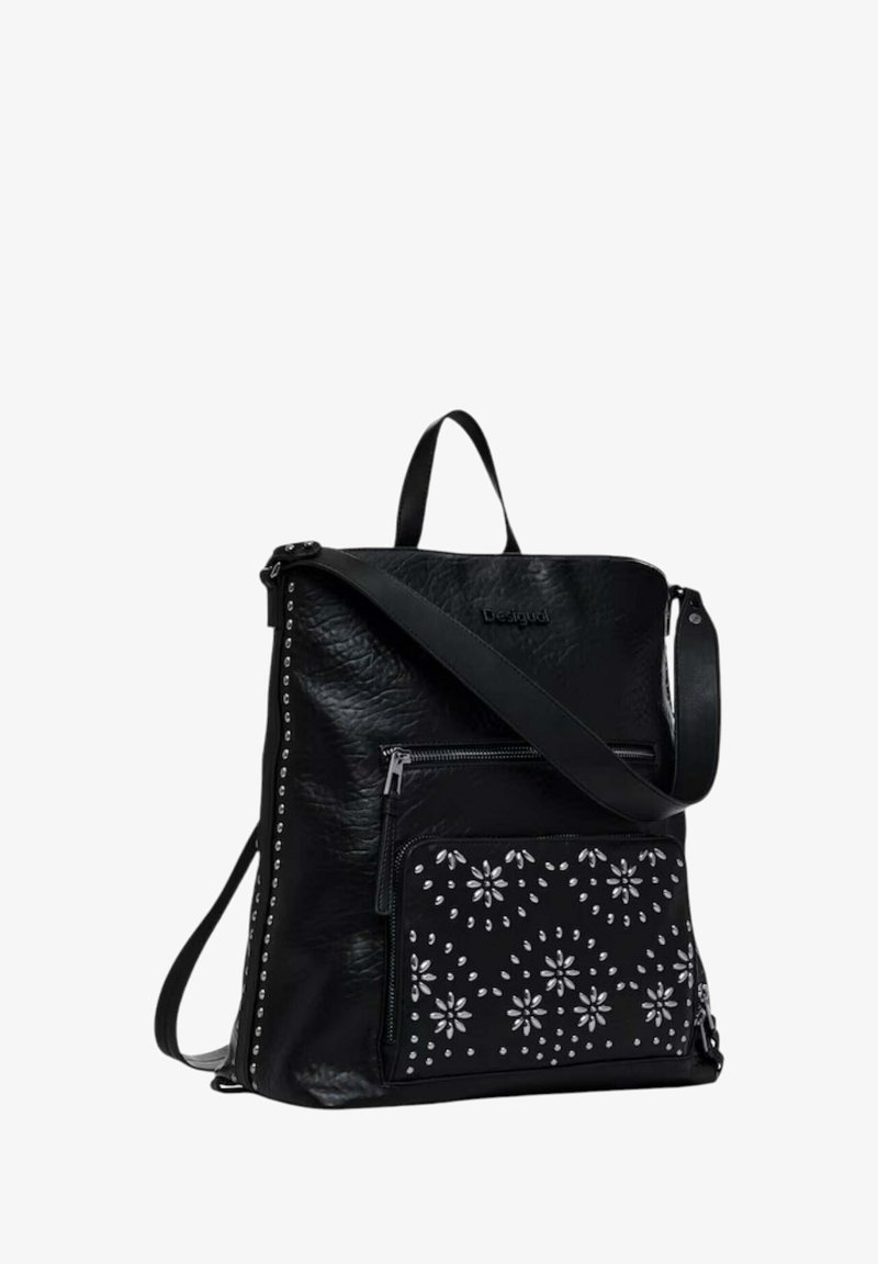 Zaino in pelle nera con corpo testurizzato, tasca frontale con zip e motivo floreale bianco, borchie argentate sui lati, spallaccio regolabile.