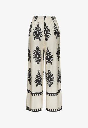 Wide-leg pants in cream fabric featuring bold black floral and geometric patterns. Elastic waistband and decorative black border at hem.