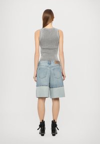 Grå ribbet tanktop med en tettsittende design, kombinert med blå denim culottes med brettet kant og et merke på livet.