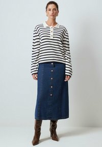 Randig långärmad topp i vitt och marinblått, med krage och knapprad, som matchas med en högmidjad denimkjol med framknappar.