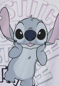 Katoenen T-shirt met een cartoonfiguur met grote zwarte ogen, een grijzige lichamele, en roze oren; de achtergrond bevat lichtpaarse tekst.