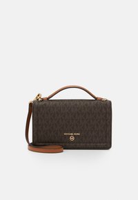 Ruskea monogrammilla varustettu crossbody-laukku, jossa on teksturoitu kankaan pinta, nahkainen olkahihna, pääkahva ja kultasävyinen logoyksityiskohta.