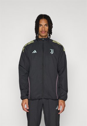 Black athletic jacket with a high collar, featuring yellow and pink accents, zip closure, and a logo on the chest. Material appears lightweight.