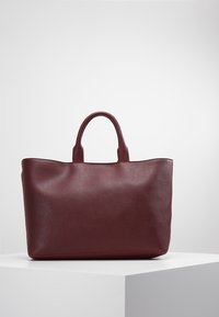 Burgundowa torba tote z gładką fakturą, mocnymi rączkami oraz minimalistycznym designem. Charakteryzuje się jednolitym kolorem i brakiem widocznego okucia.